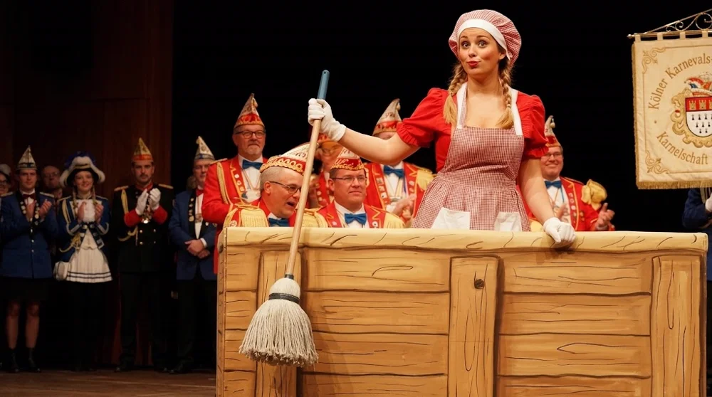 Karnevalistin steht in traditioneller hölzerner Bütt und hält eine humorvolle Büttenrede